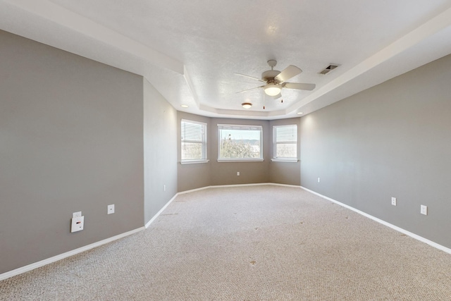 carpeted empty room featuring ceiling fan and a tray ceiling