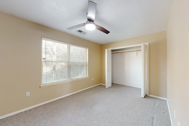 unfurnished bedroom featuring ceiling fan, light colored carpet, and a closet