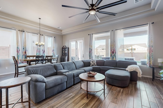 living room featuring hardwood / wood-style flooring, ceiling fan with notable chandelier, and a tray ceiling