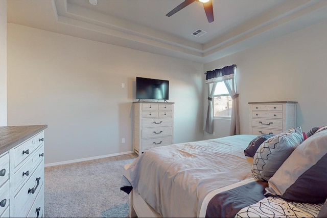 bedroom with light colored carpet, a raised ceiling, and ceiling fan