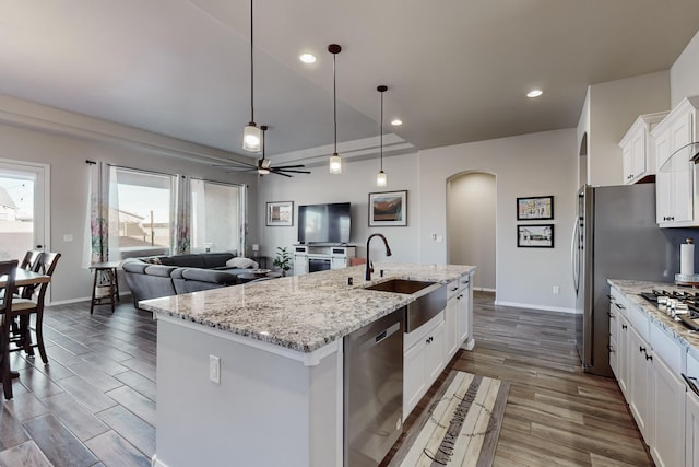 kitchen with pendant lighting, a kitchen island with sink, sink, white cabinetry, and stainless steel appliances