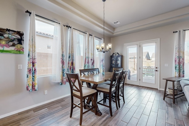 dining area with a tray ceiling, a healthy amount of sunlight, and a notable chandelier