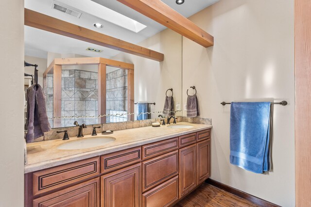 bathroom with a skylight, vanity, and hardwood / wood-style flooring