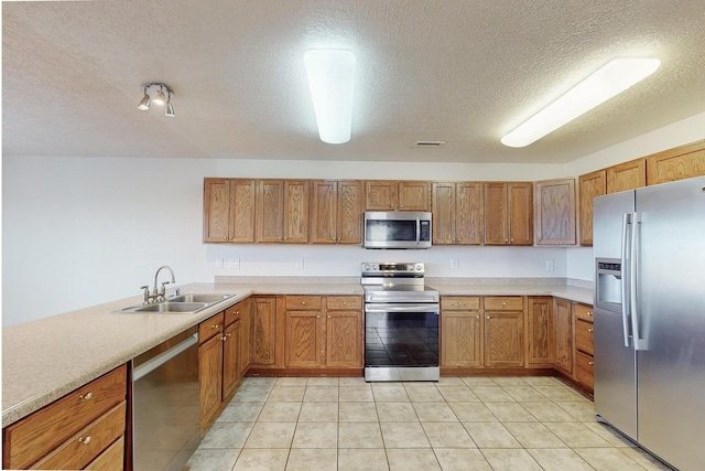 kitchen with a textured ceiling, light tile patterned flooring, sink, and stainless steel appliances