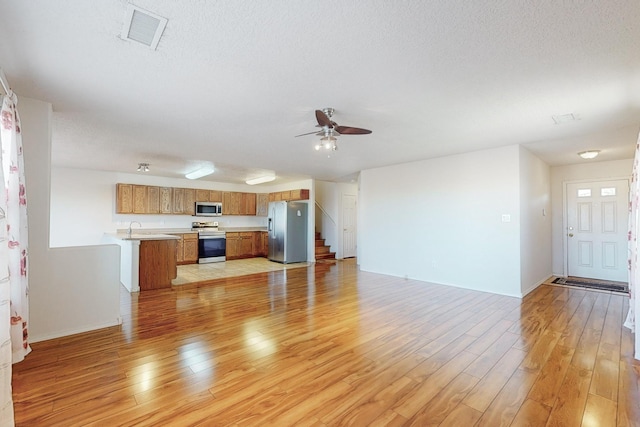 unfurnished living room featuring a textured ceiling, light wood-type flooring, and ceiling fan