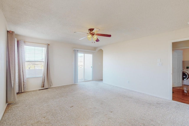 carpeted empty room with a textured ceiling, washer / clothes dryer, and ceiling fan