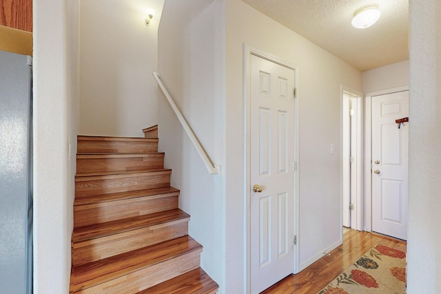 stairway with hardwood / wood-style flooring and a textured ceiling