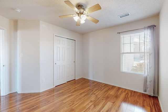 unfurnished bedroom featuring ceiling fan, a closet, light hardwood / wood-style floors, and a textured ceiling