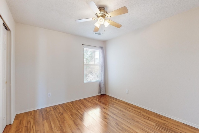 spare room with ceiling fan, light wood-type flooring, and a textured ceiling