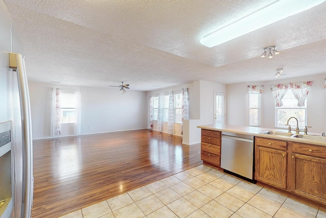 kitchen featuring ceiling fan, sink, stainless steel appliances, a textured ceiling, and light tile patterned flooring