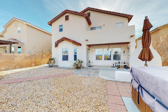 rear view of property with a hot tub and a patio area