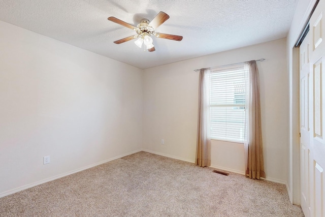 empty room with a textured ceiling, light colored carpet, and ceiling fan