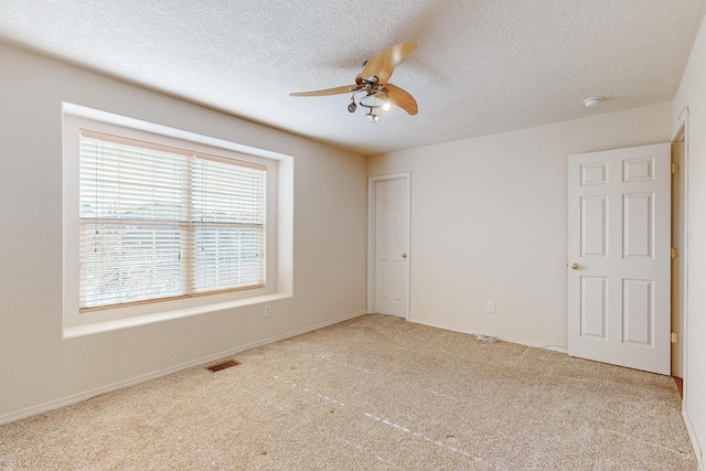 carpeted spare room featuring ceiling fan and a textured ceiling