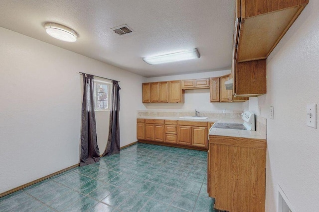 kitchen with tile counters, sink, a textured ceiling, and range