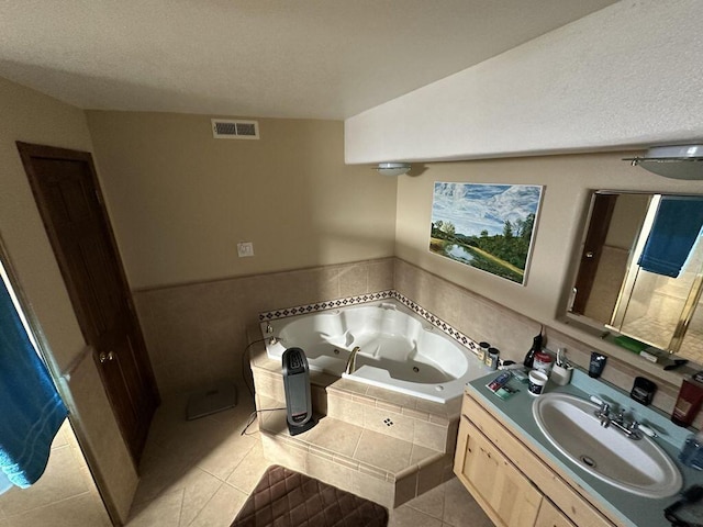 bathroom with tile patterned floors, tiled tub, and vanity