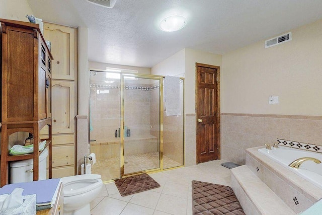 bathroom featuring tile patterned floors, toilet, a textured ceiling, shower with separate bathtub, and tile walls