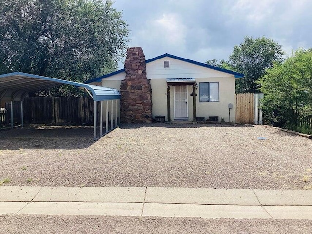 bungalow-style house featuring a detached carport, fence, and a chimney