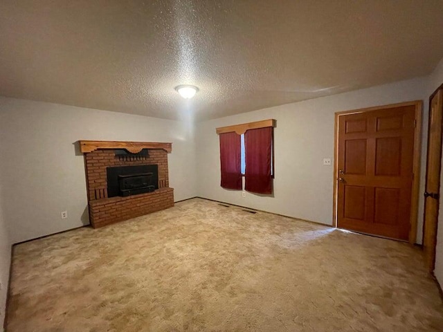 unfurnished living room with a textured ceiling, a brick fireplace, and carpet flooring