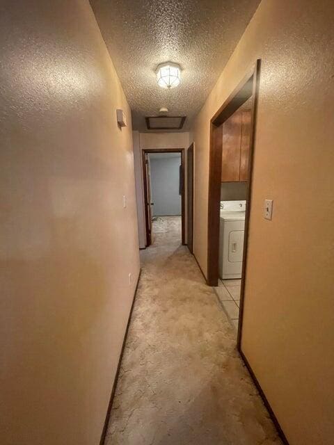 corridor featuring a textured ceiling and washer / clothes dryer