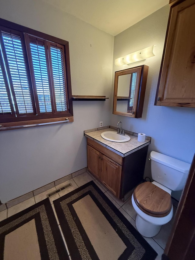 half bathroom with vanity, tile patterned floors, toilet, and visible vents