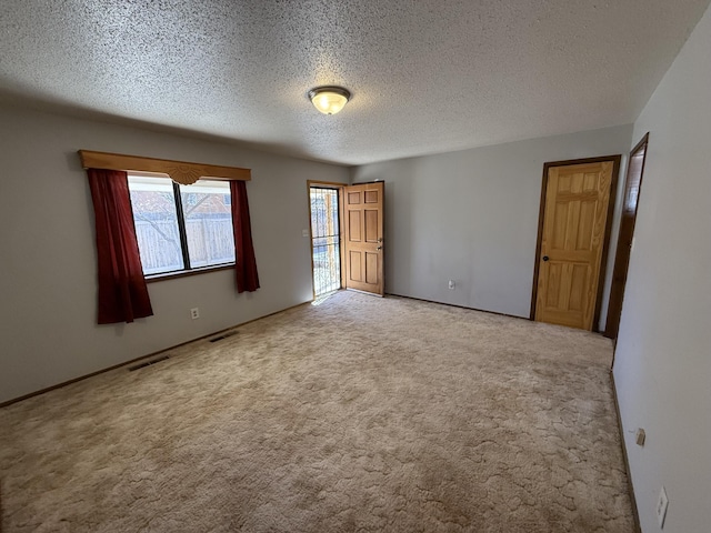 unfurnished room featuring visible vents, a textured ceiling, and carpet floors