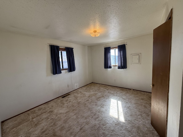 carpeted spare room featuring visible vents and a textured ceiling