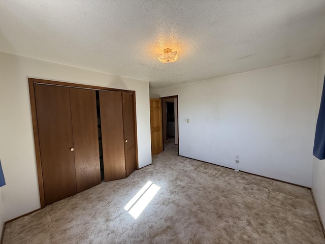 unfurnished bedroom featuring a textured ceiling, a closet, and light carpet