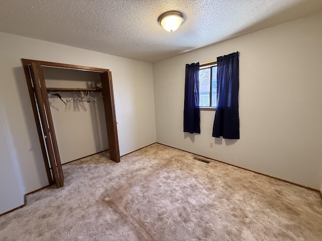 unfurnished bedroom featuring a closet, visible vents, carpet flooring, and a textured ceiling