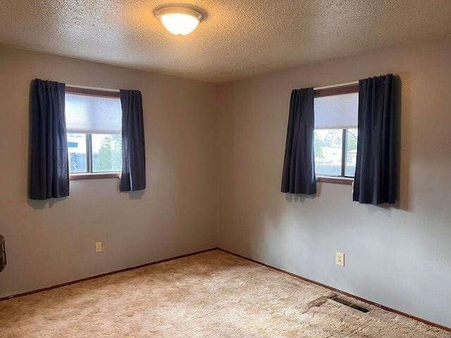 carpeted empty room with visible vents and a textured ceiling