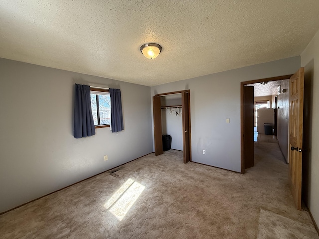 unfurnished bedroom featuring a closet, light colored carpet, and a textured ceiling