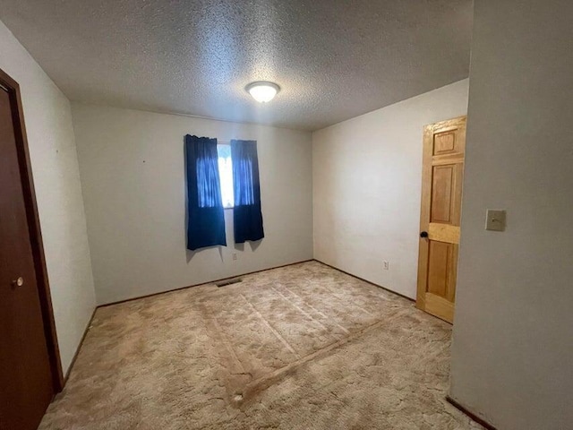 carpeted spare room with visible vents and a textured ceiling