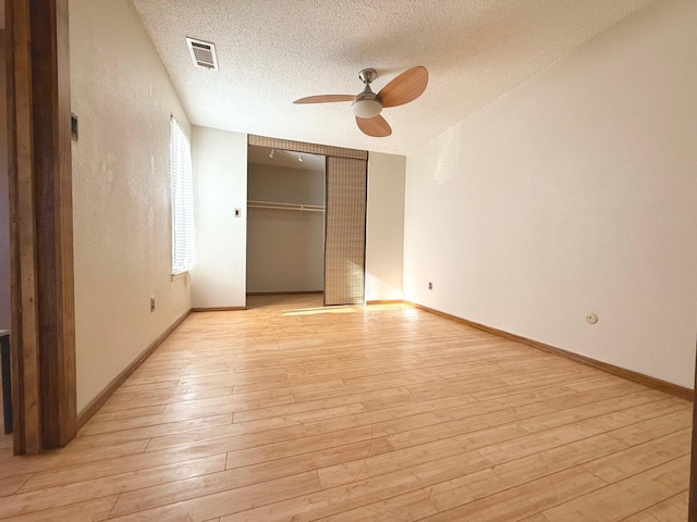 unfurnished bedroom featuring a textured ceiling, a closet, ceiling fan, and light hardwood / wood-style floors