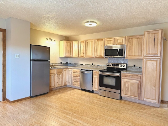 kitchen featuring sink, light brown cabinets, light wood-type flooring, and appliances with stainless steel finishes