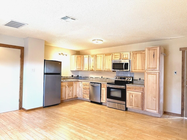 kitchen featuring appliances with stainless steel finishes, light wood-type flooring, light brown cabinetry, and sink