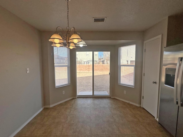 unfurnished dining area featuring a textured ceiling and a chandelier