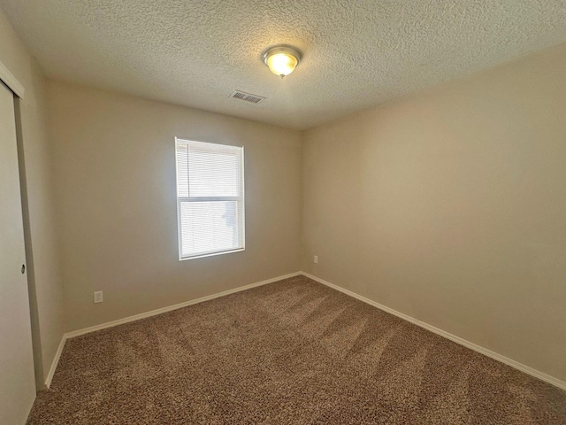 spare room with carpet flooring and a textured ceiling