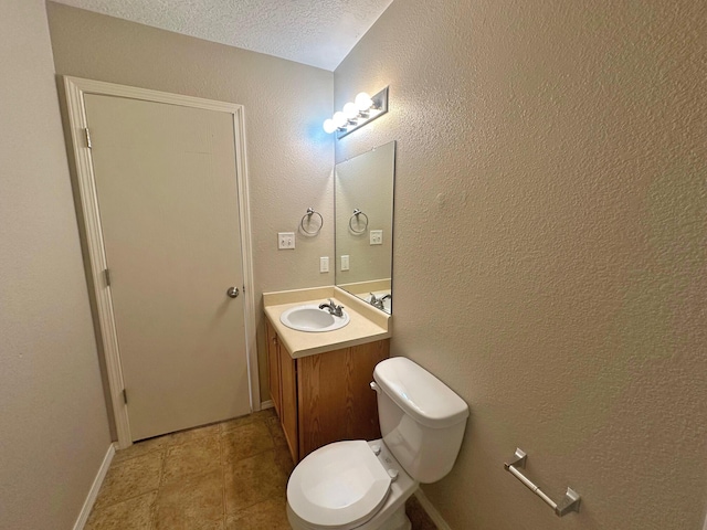 bathroom featuring toilet, a textured ceiling, and vanity