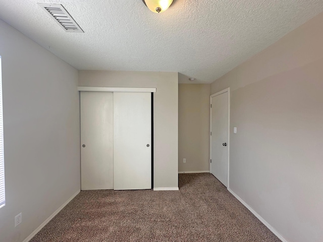 unfurnished bedroom with a closet, a textured ceiling, and carpet floors