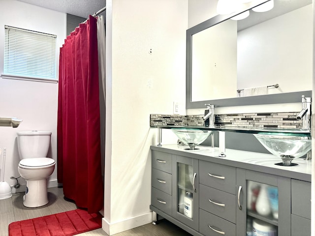 bathroom with tasteful backsplash, curtained shower, vanity, and toilet