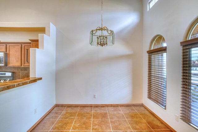 unfurnished dining area with an inviting chandelier and tile patterned flooring