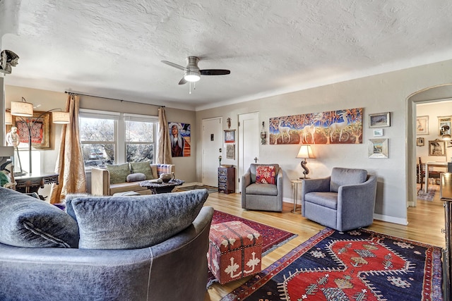 living room with hardwood / wood-style floors, ceiling fan, and a textured ceiling