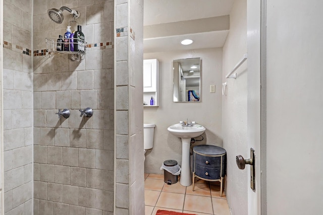 bathroom featuring tile patterned flooring, a tile shower, and toilet