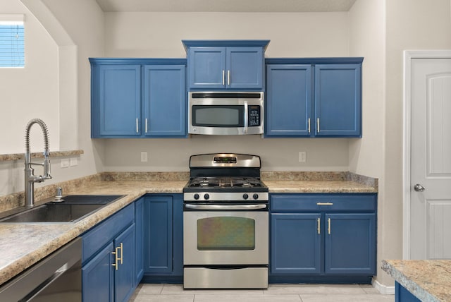 kitchen featuring blue cabinetry, sink, light tile patterned floors, and stainless steel appliances