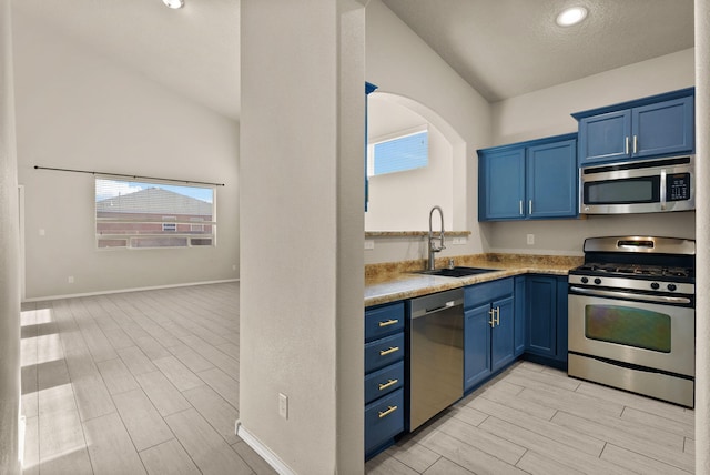 kitchen featuring blue cabinets, sink, appliances with stainless steel finishes, and vaulted ceiling