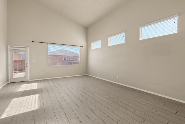 spare room featuring high vaulted ceiling and light hardwood / wood-style flooring