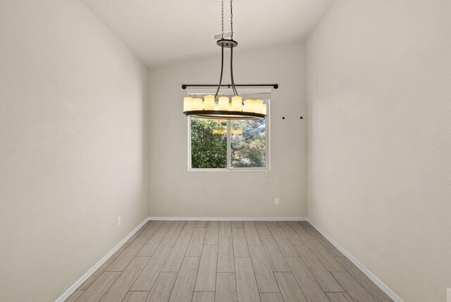 unfurnished room with light hardwood / wood-style floors and lofted ceiling