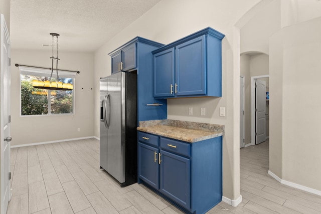 kitchen featuring blue cabinetry, lofted ceiling, a textured ceiling, and stainless steel refrigerator with ice dispenser