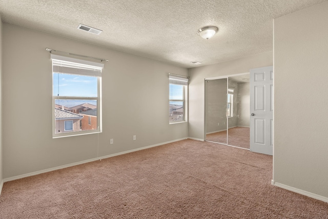 unfurnished bedroom featuring a textured ceiling, light carpet, and a closet