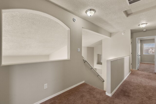 corridor with carpet flooring and a textured ceiling