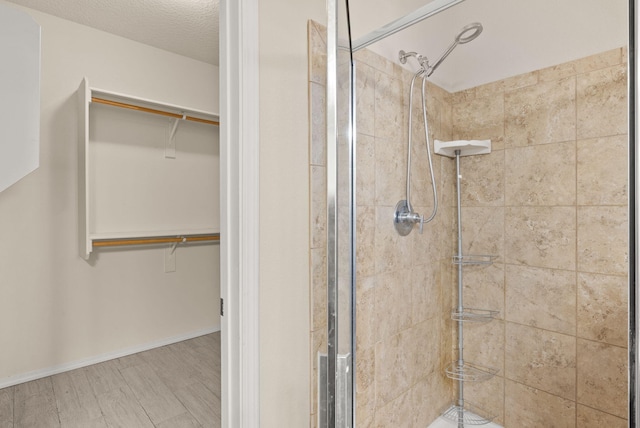 bathroom with a shower with door, hardwood / wood-style floors, and a textured ceiling